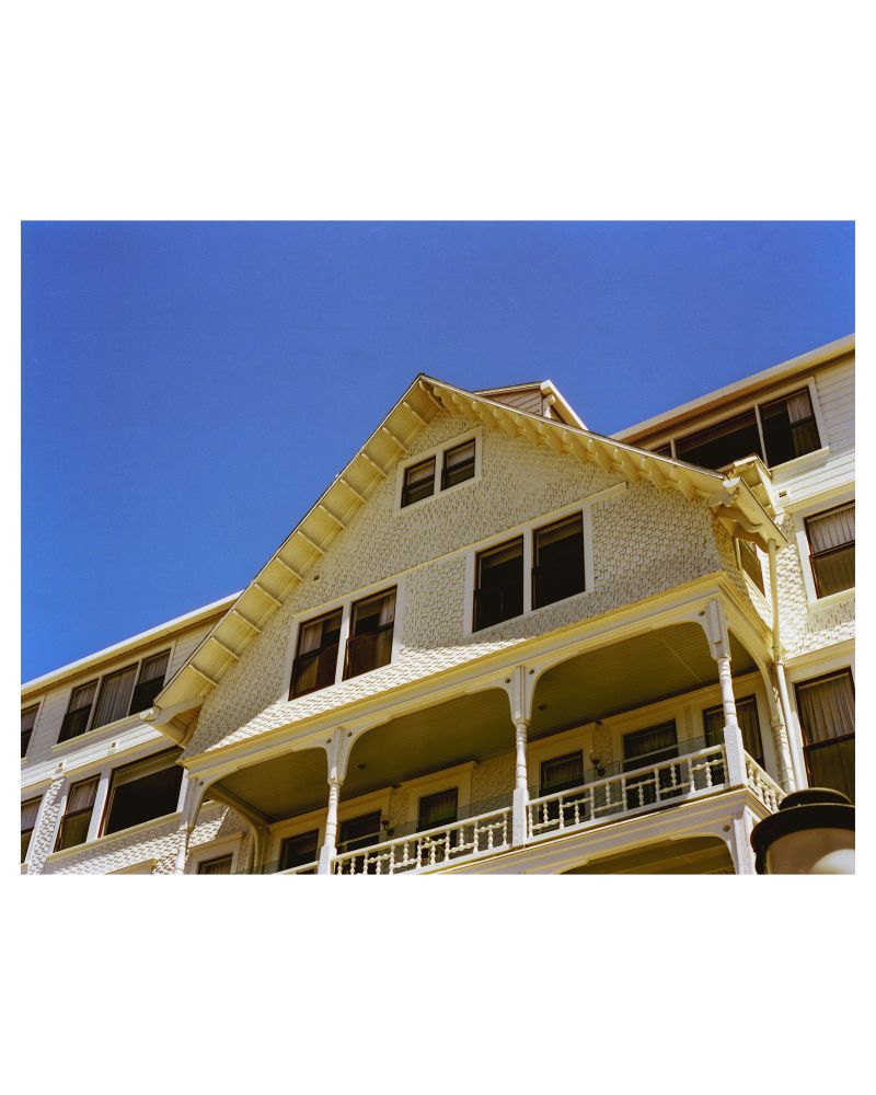 A photograph of a balcony of the Hotel del Coronado. In the photograph, the bright white siding can be seen with all of its intricate detailing absent from the previous images. 