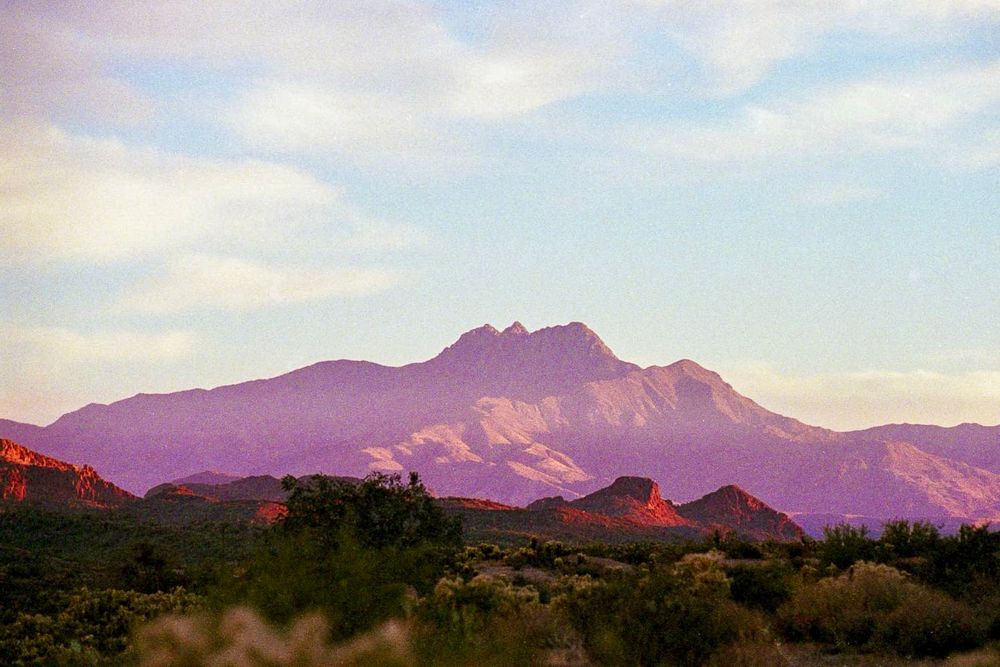 A photograph of Four Peaks taken on 35mm film. In the photo, the Peaks are the main focus, framed by the smaller mountains and flora of the Southwest. 