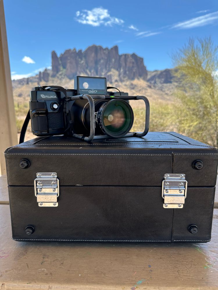 A photograph of the Fuji G617 sitting on its original case. In the background, the Superstition Mountains can be seen towering over the desert landscape. 
