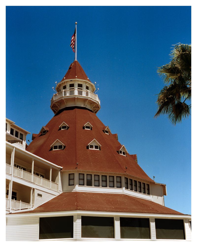 A photograph of the rotunda at the Hotel del Coronado. The distinctive brown shingles wrap around the building and provide stark contrast to the bright white siding. 