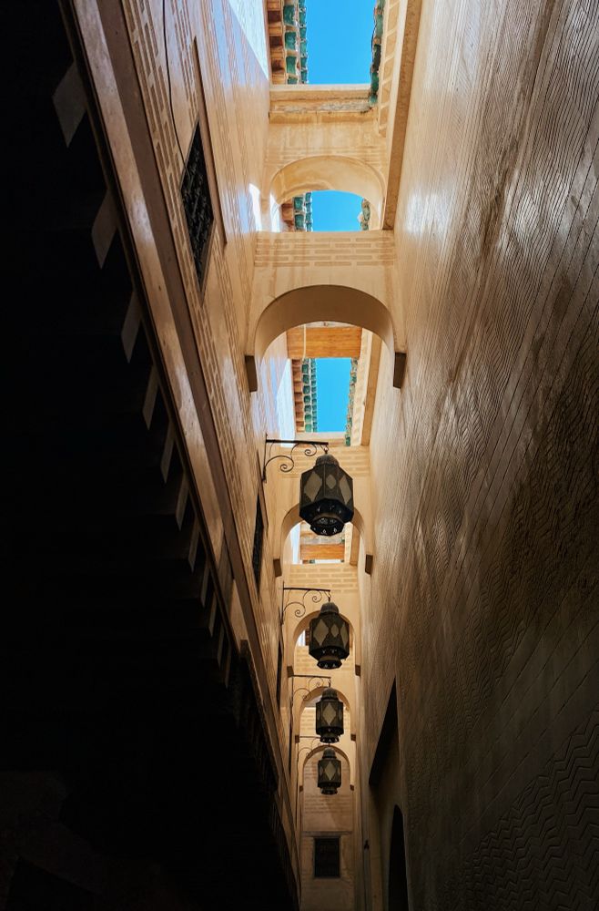 A row of arches and lamps hang above the alley next to the Mosque and University of al-Qarawiyyin.