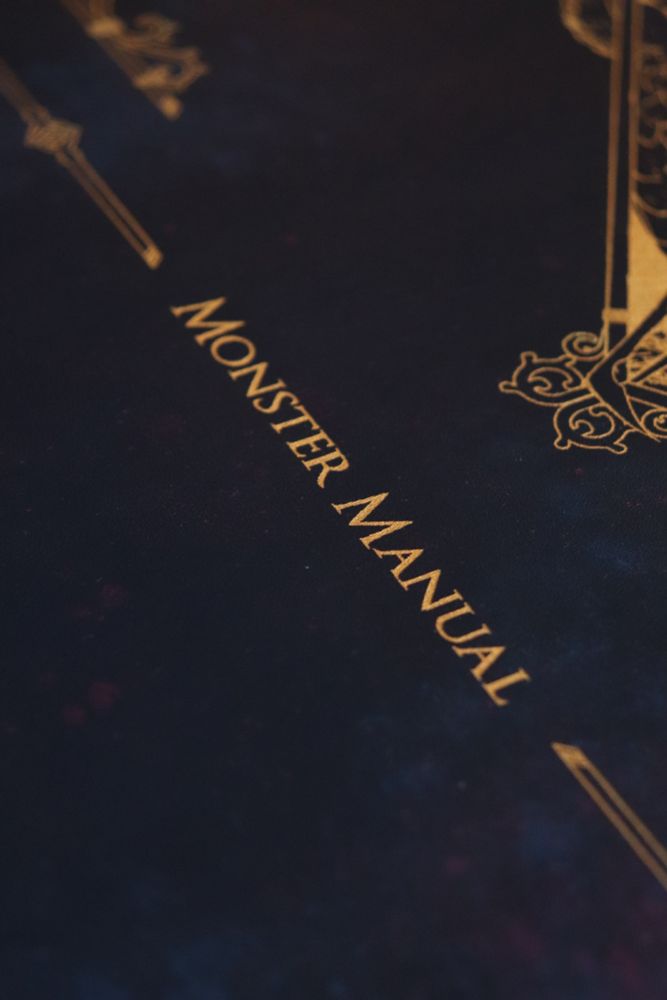 The text 'Monster Manual' in gold on blue leather