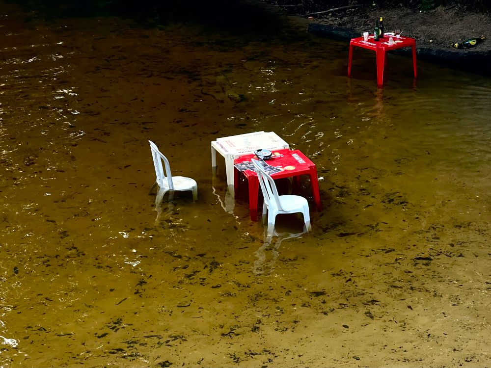 cadeiras e mesa de plástico no deságüe da cachoeira 
