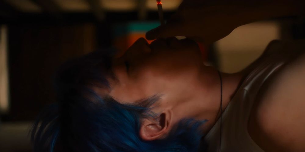under her bed, he smokes her cigarette. his bright blue hair complements her blue dress. 