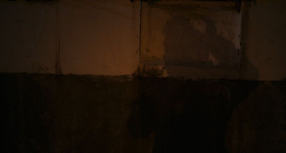sung-sik's shadow reveals the back of his head is missing. he touches the wound, a cigarette hanging from his lips. 