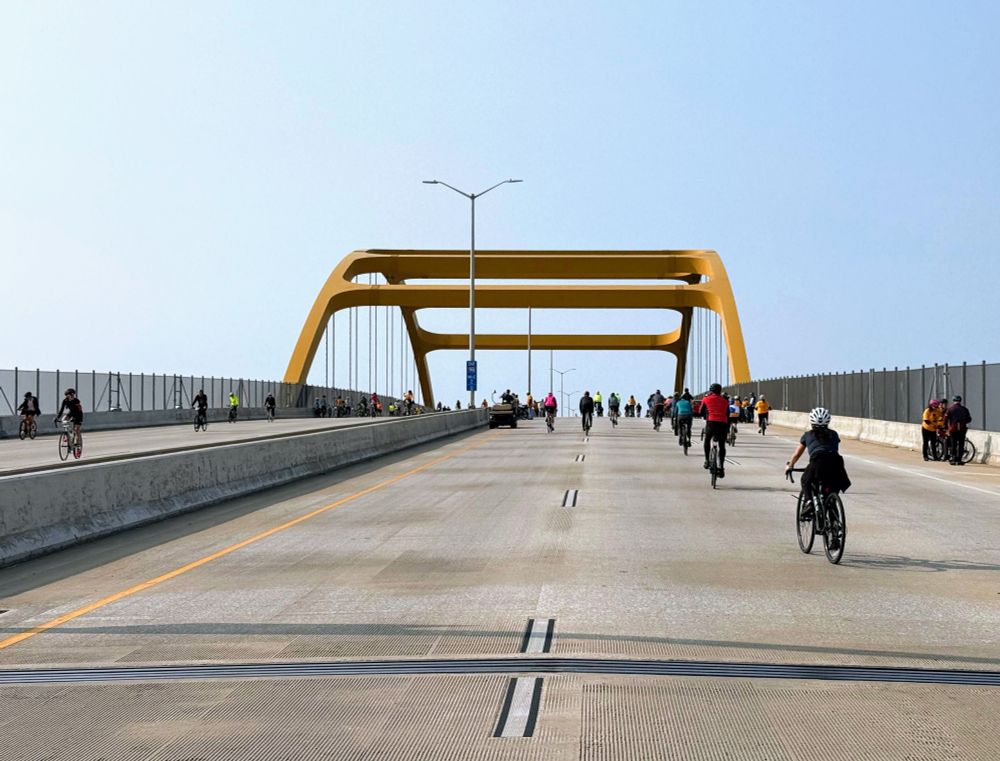 The Hoan Bridge in Milwaukee, WI during a day when it is closed to motor traffic and open to cyclists. The bridge is very tall and has yellow arches