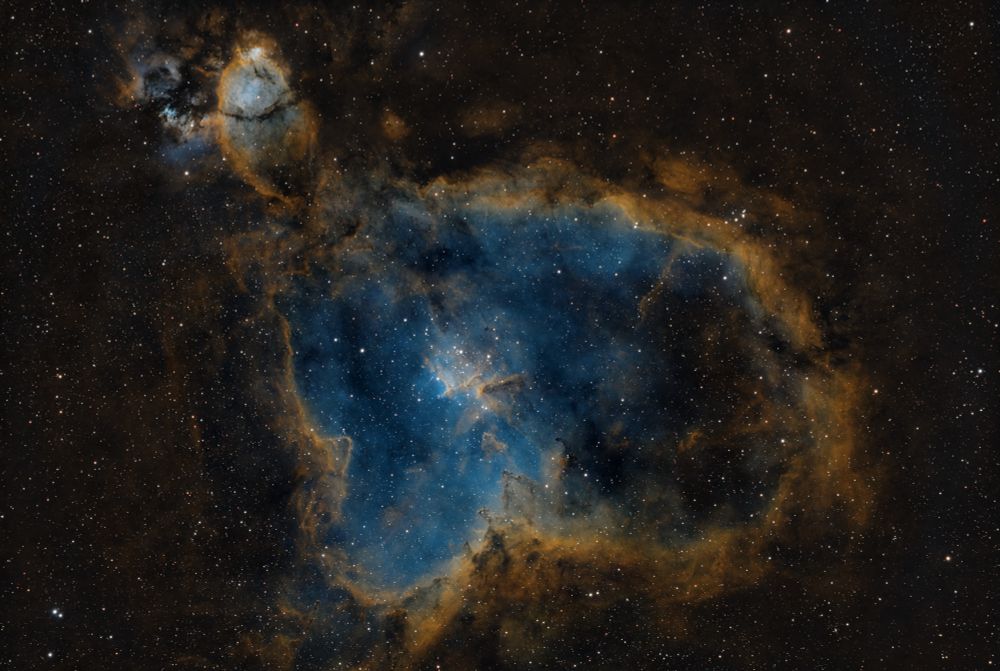 Image of the bright emission nebula IC 1805 which is commonly named the Heart Nebula due to its shape resembling a heart. The inner core looks like a blue lake here because the OIII emission is rendered blue in the SHO colour palette. In its centre there is a prominent open star cluster with a peculiar pillar of dust. This area has the designation Melotte 15.