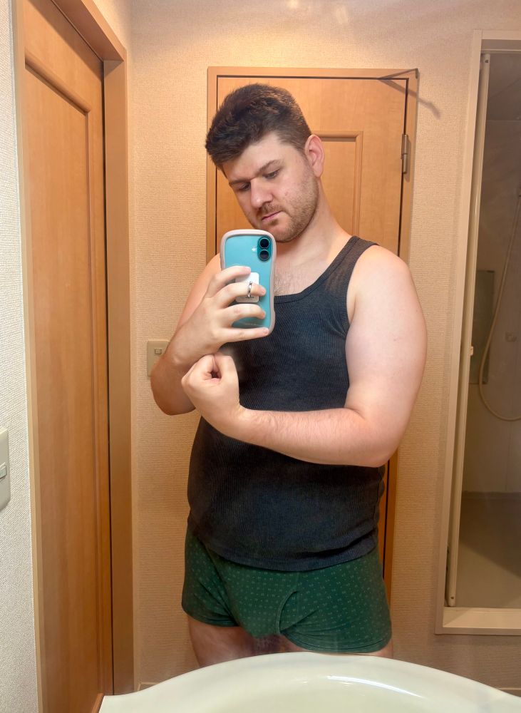 Selfie of Mikey in the mirror in a tank top showing arm 