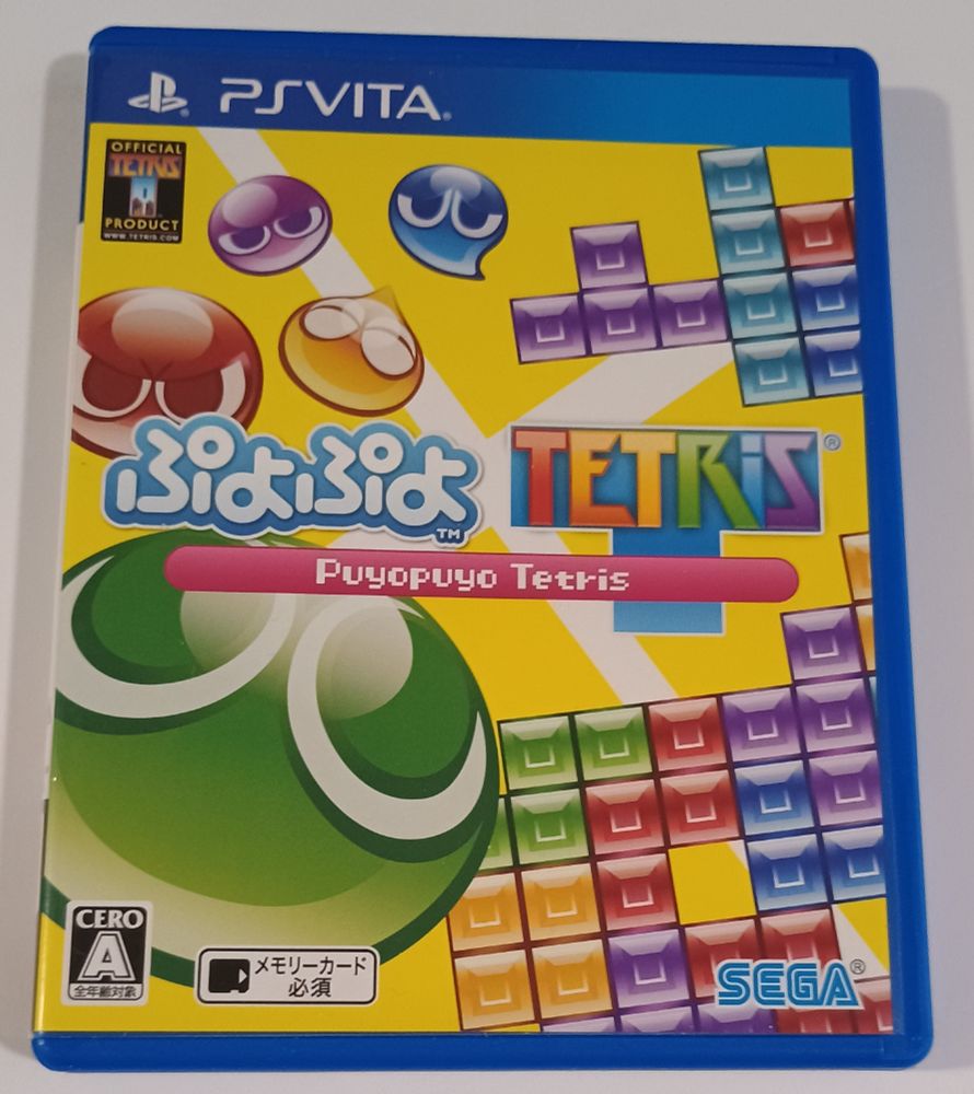 Cover of Puyo Puyo Tetris for the Playstation Vita.  Features some Puyos and Tetriminos against a yellow background.