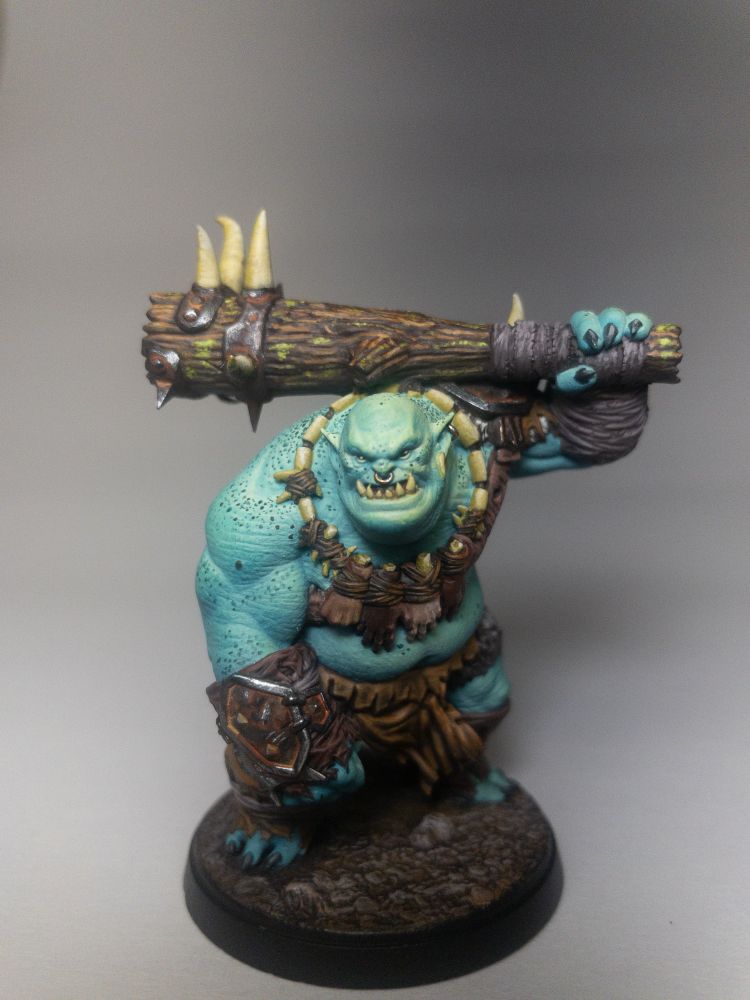 Hand painted teal blue Ogre miniature wielding a club draped in the hands and bones of his victims.