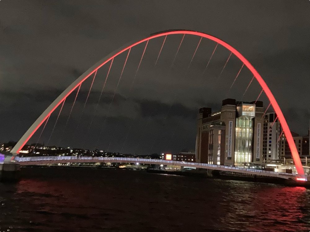 Red arch across the river Tyne at night is the Millennium Bridge