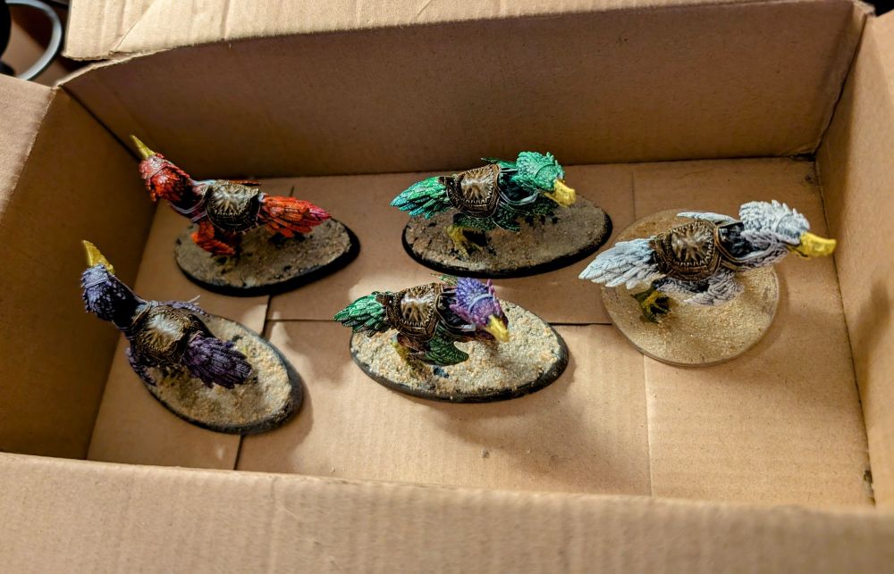 Painted axe beak DnD monster miniatures drying in a box.