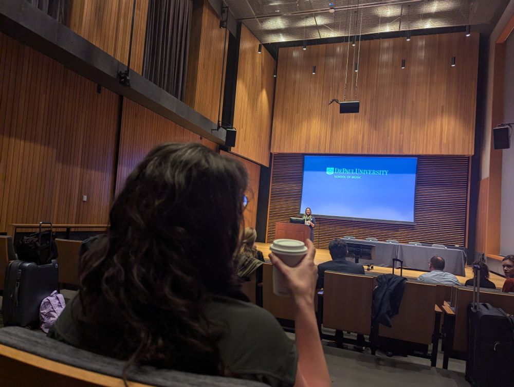 Interior of an auditorium with a large blue screen reading "DePaul University School of Music" 