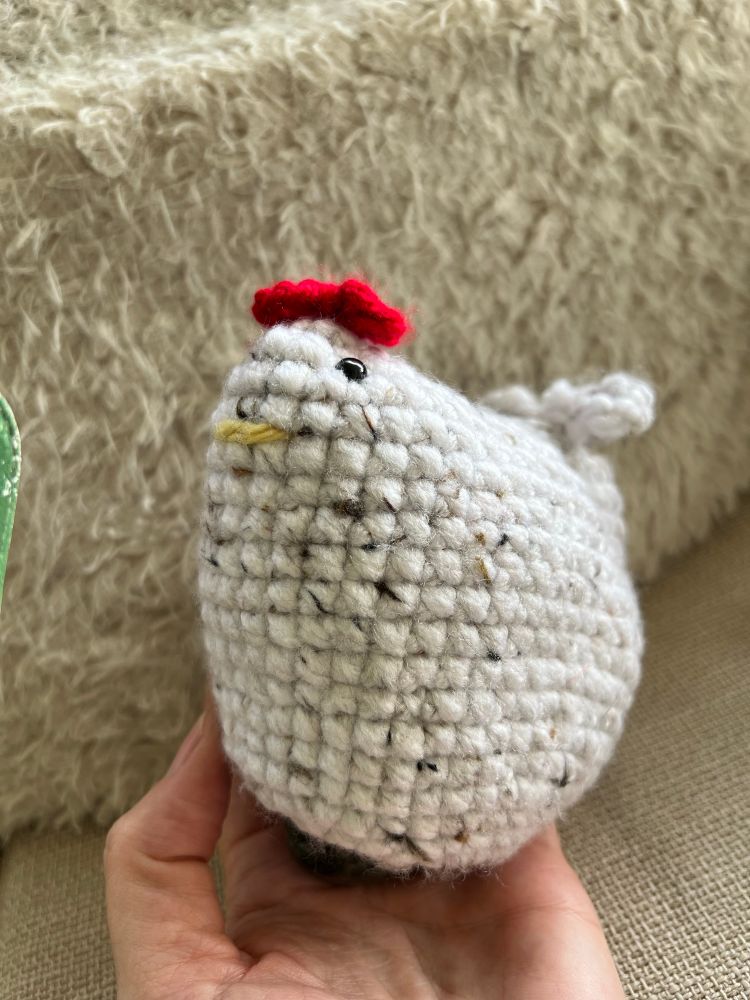 Cream colored Crochet Chicken with the size of a egg shaped concave where it should actually be flat on the bottom with a Wyoming jade Stone in the shape of an egg from the stone femme rock and gem shop in Montrose