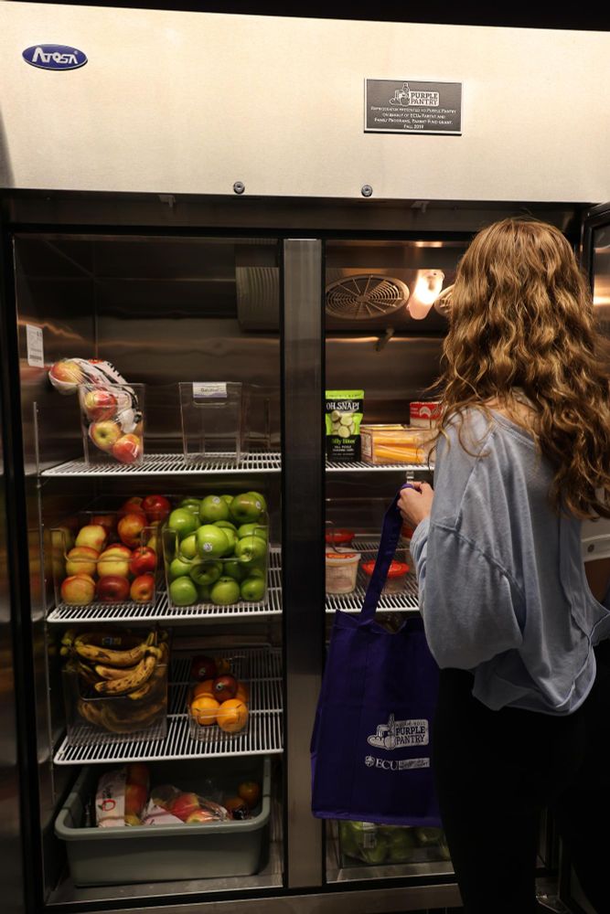Individual is selecting fresh produce from Purple Pantry fridge. 