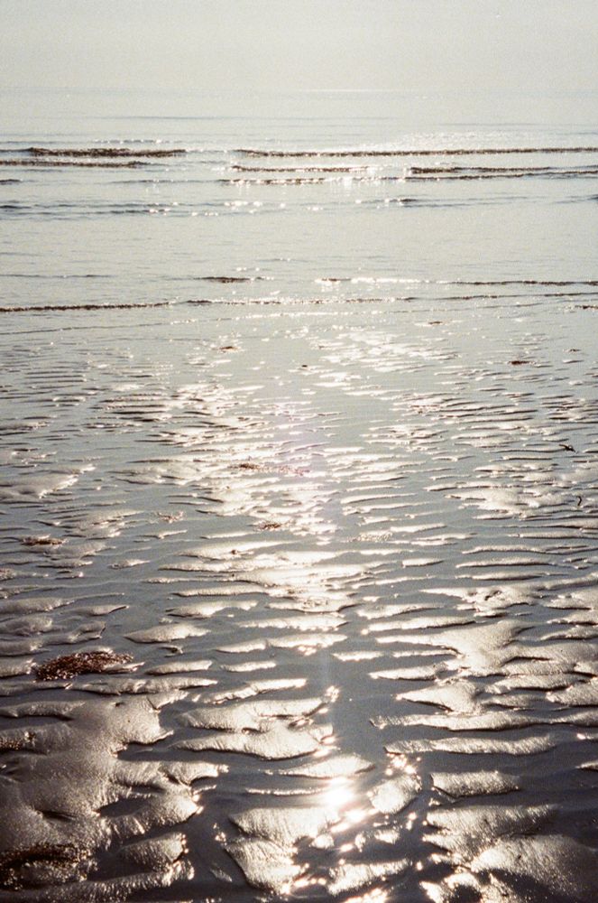 Sunlight reflecting on rippling wet sand on a beach