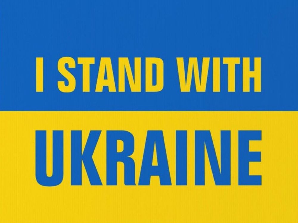 "I Stand With Ukraine" printed on a blue and yellow Ukrainian flag.  