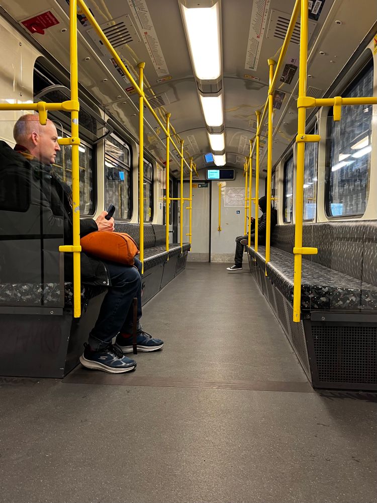 En nästan tom tunnelbanevagn i Berlin. En man sitter nära i bilen och en längst bort. 