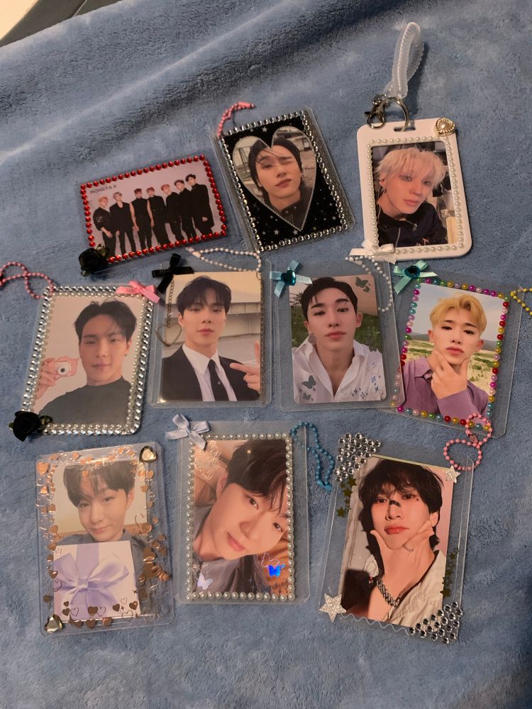 Photocards of monsta x, shownu, Wonho, btob changsub, eunkwang, and b.a.p jongup  in 10 decorated hard photocard sleeves with stickers, bows, roses, keychains on them. 