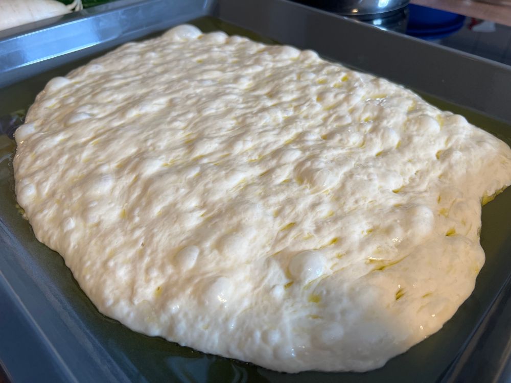 Ein Backblech mit einem Hefeteig, der viele große Blasen wirft