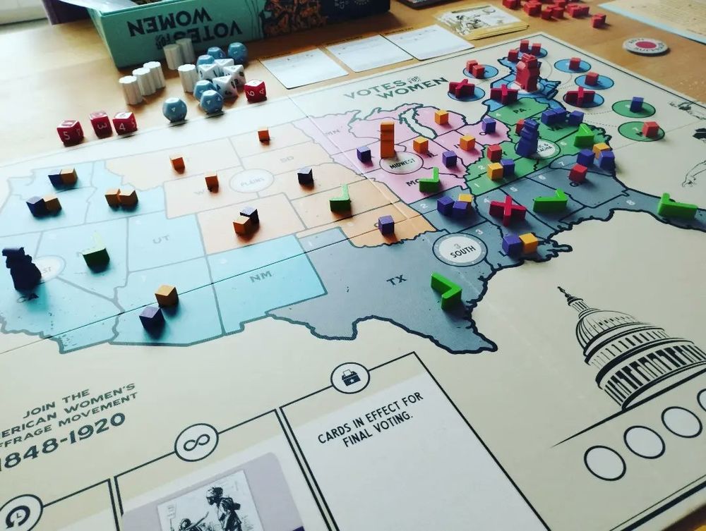 The Board Game Votes for Women is laid out on a table in somewhat dramatic lighting