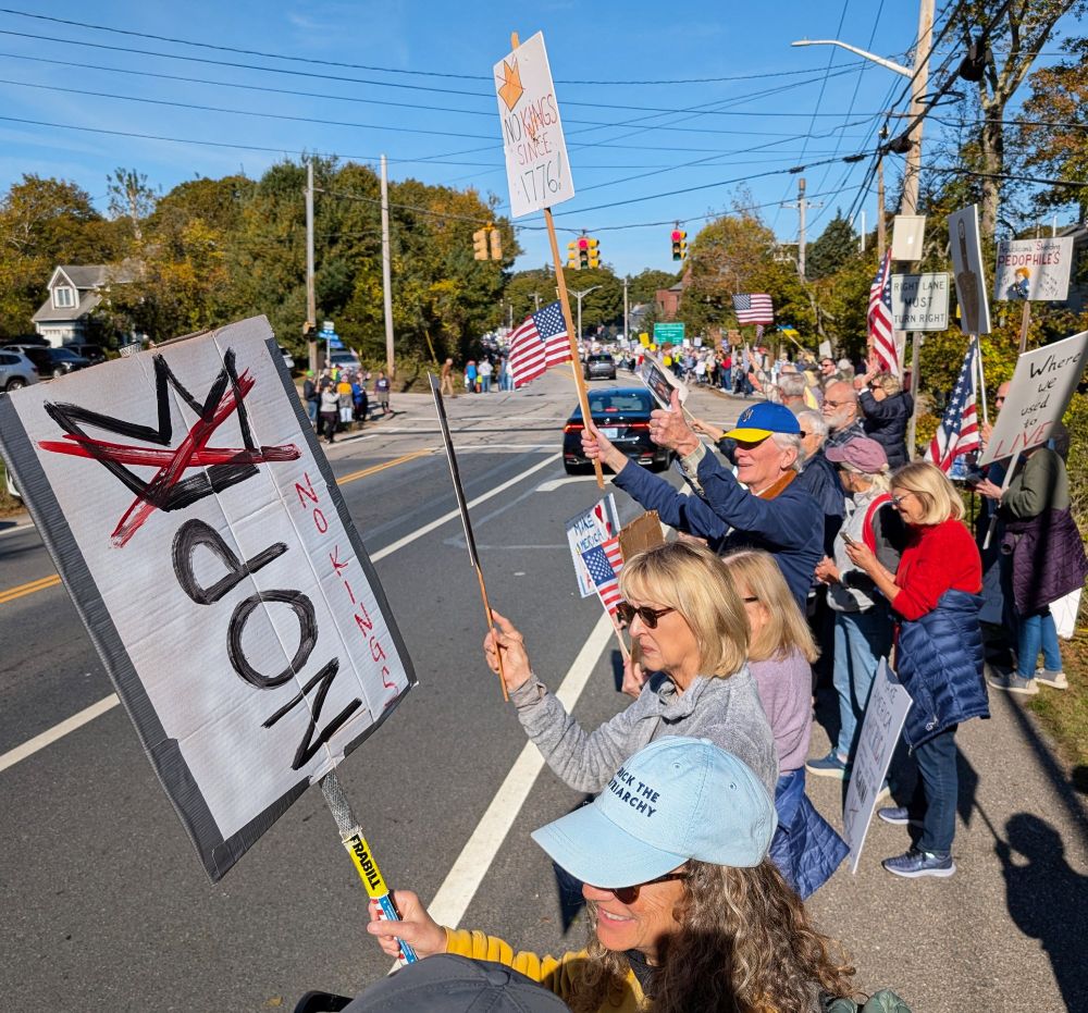 Crowds of protestors holding signs line a local roadway