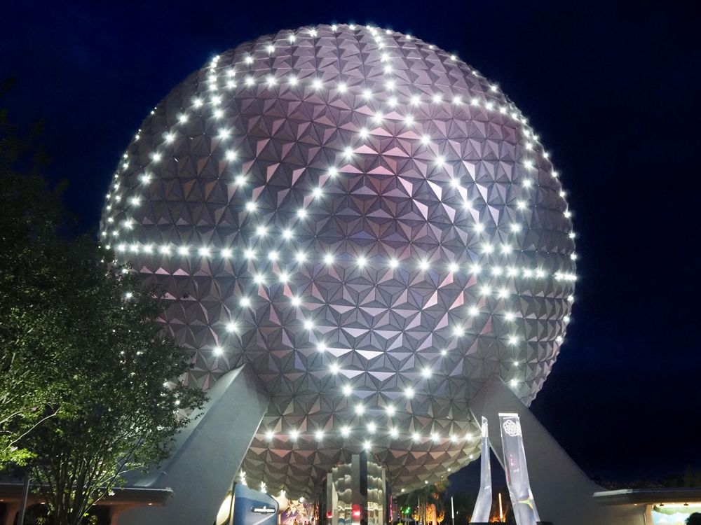 Spaceship Earth at night with ribbons of white light around it