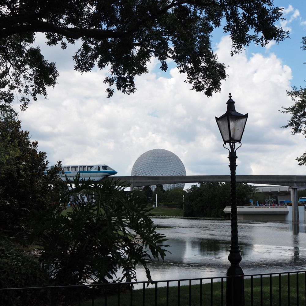 Monorail Blue is about to pass in front of Spaceship Earth as it goes over a waterway. 