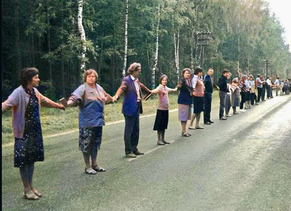 People in a long line joining hands 