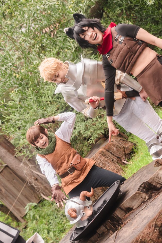 from left to right, Lizy, Dana, and connie cosplaying as Chilchuk, Laios, and Izutsumi. Senshi's severed head is in a wok on a tree stump. Lizy is holding her head while gesturing to Senshi with a look of shock. Dana is looking at the head with a slight smile with one hand on Kensuke. connie is poiting at the head with an open mouthed smile. 
