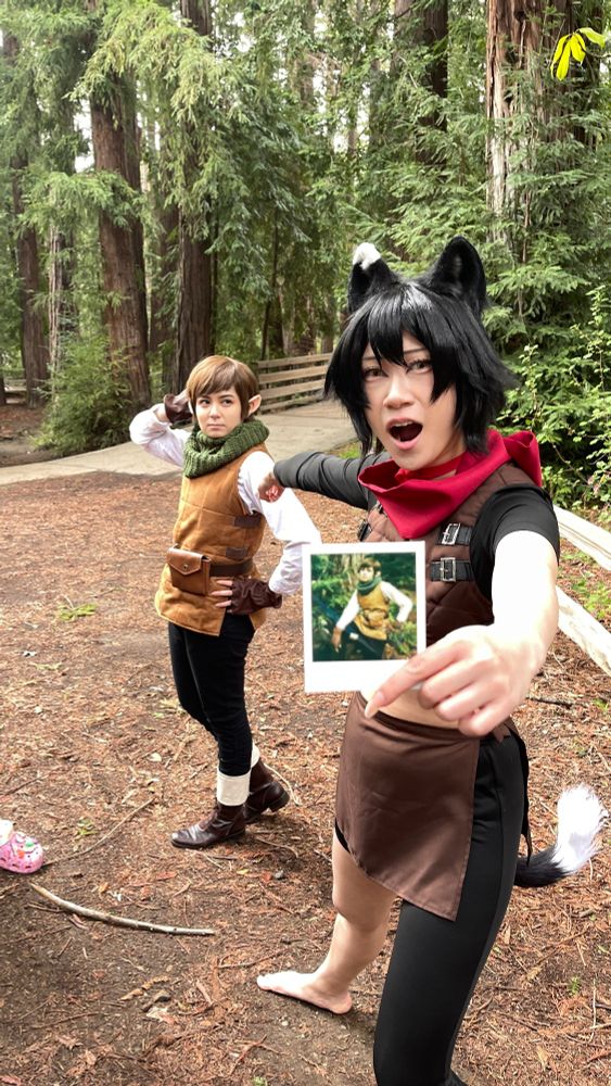 a photo of connie cosplaying Izutsumi and Lizy cosplaying Chilchuck. connie is holding a polaroid while pointing at Lizy, who is doing a cool pose. The polaroid is a photo of Lizy doing a different, but equally cool pose. 