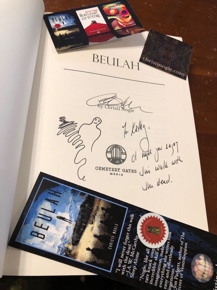 Signed title page with a sticker, bookmark, and business card. “To Kathy, I hope you enjoy this walk with the dead” next to a sketch of a squiggly shadow and a ghost