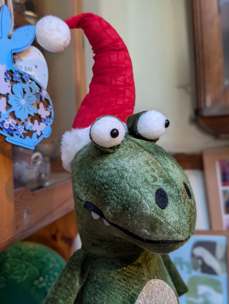 Wide-eyed upright dinosaur in a Santa hat