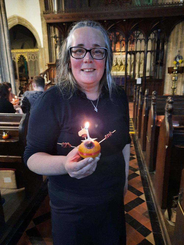 Lead Evangelist, Hanna Seal, smiles as she holds a lit Christingle.