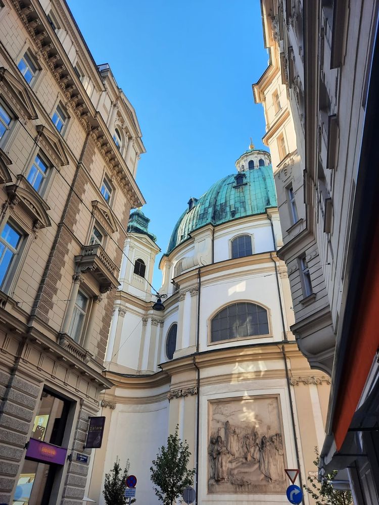 Peterskirche, Vienna. A church with a green copper roof under a bright blue sky, at the end of a street in Vienna