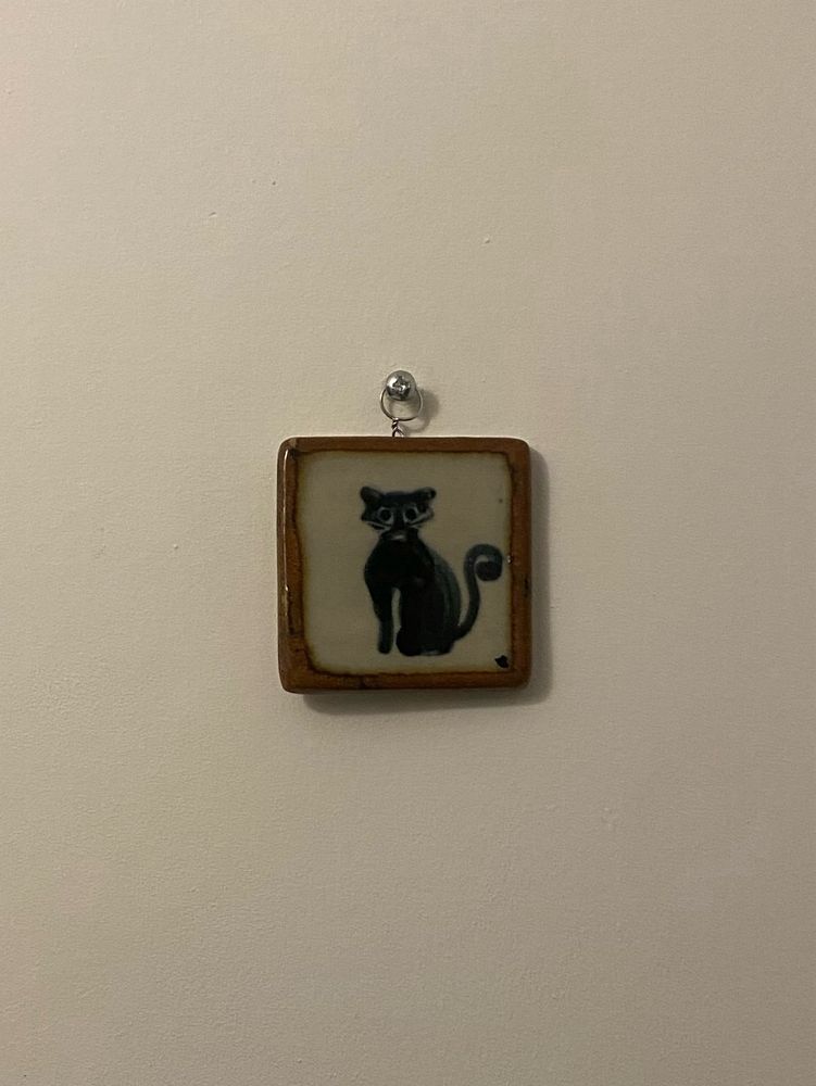 Small ceramic tile depicting a black cat