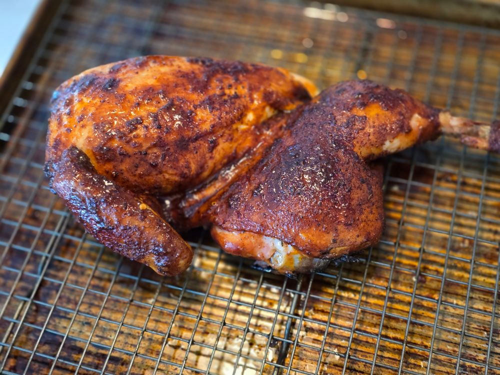 A picture of half of a smoked chicken seasoned with Meat Church Hickory rub and finished with Swamp Tonic.