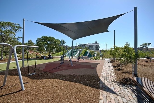 Playground with a sail raised and stretched over it, providing a lot of shade. 