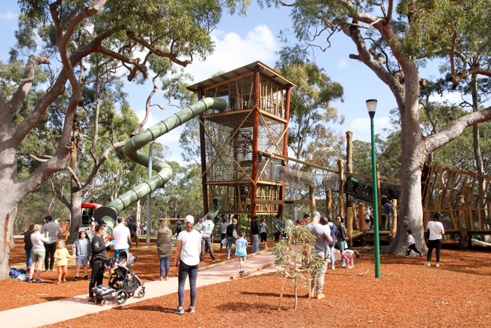 A playground with a large wooden tower climbing structure, maybe 30 meters tall, with a roof. Giant slide swirls down from the top.