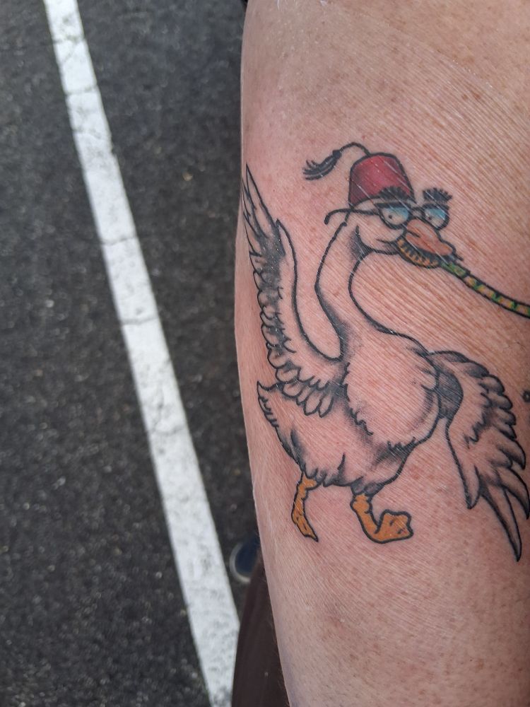 An image of a goose wearing glasses and a fez, while blowing a party noisemaker