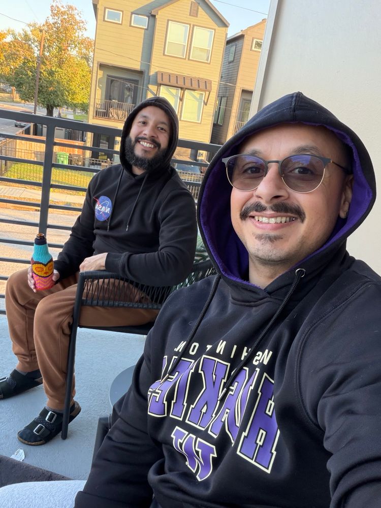 Me and my partner sitting on the balcony on a sunny afternoon. It’s chilly so we are wearing hoodies  