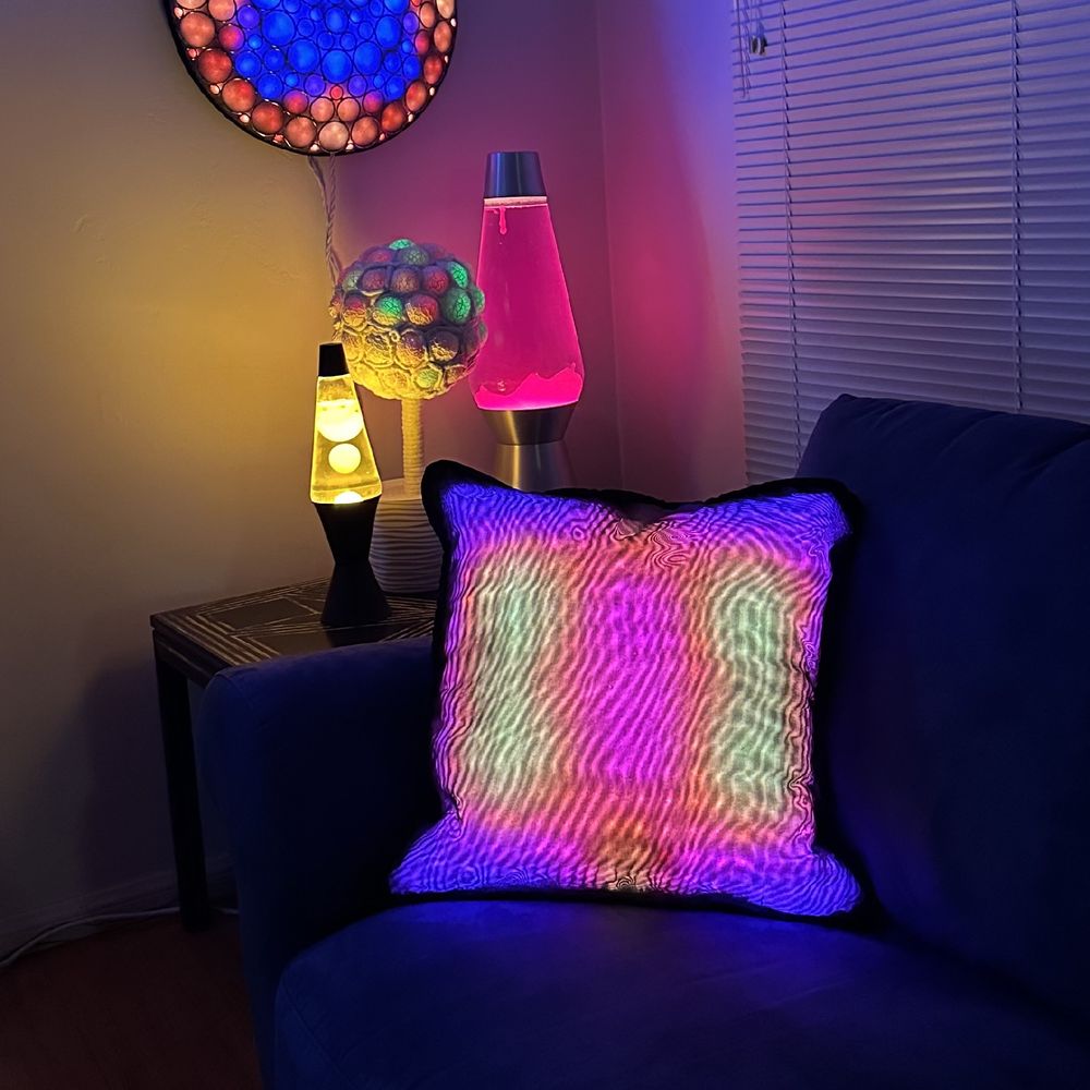 light up pillow on a couch in a room with lava lamps and other artistic lighting
