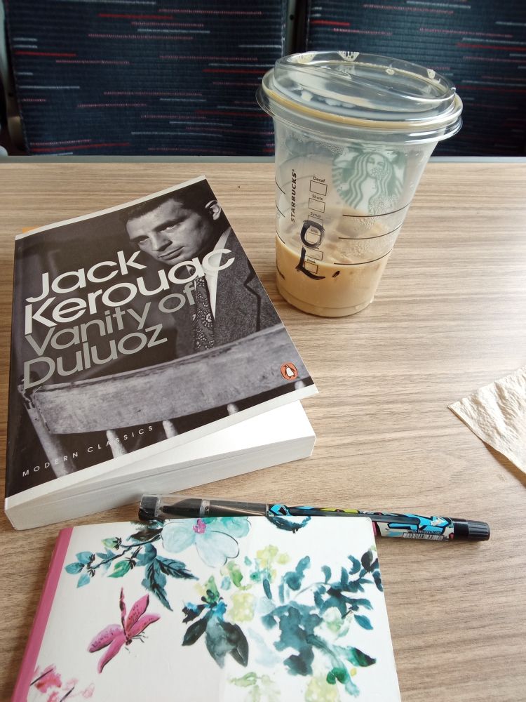 Picture of jack Kerouac book vanity of duluoz, a half empty coffee cup on a train tablw