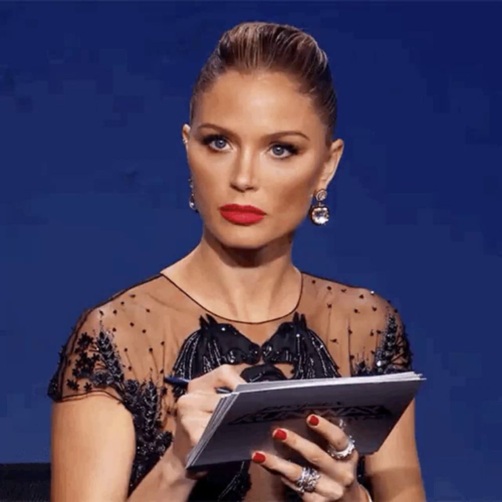 a woman in a black dress is holding a piece of paper in her hands .