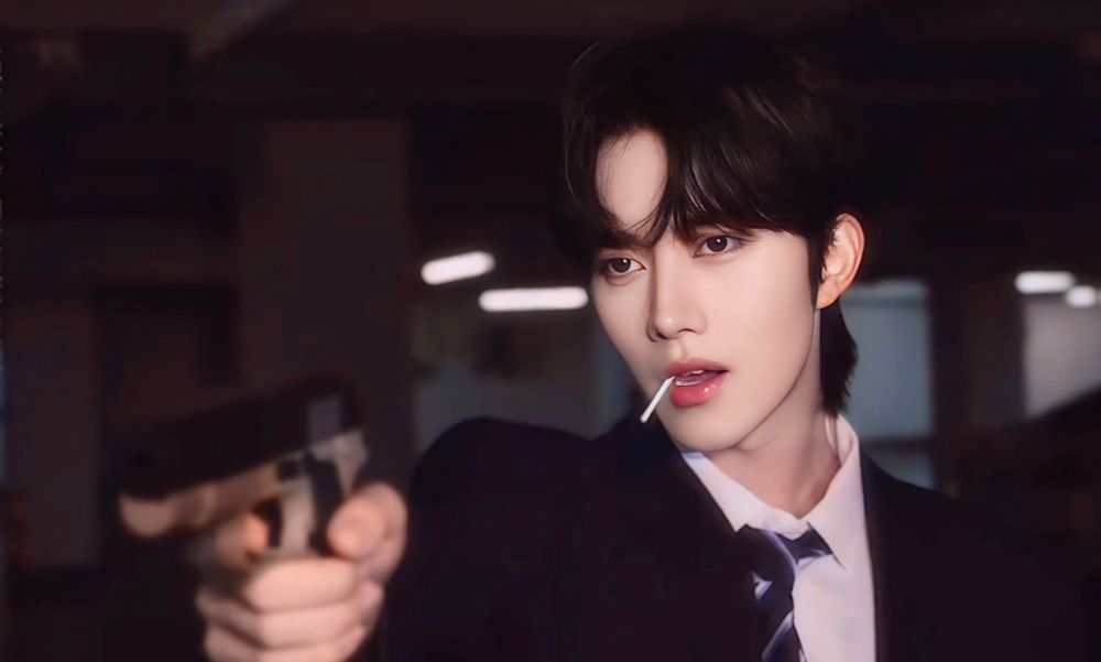 Still from Desire. Eliot Huang pointing a gun and sucking on a lollipop. Very gangster. And hot.