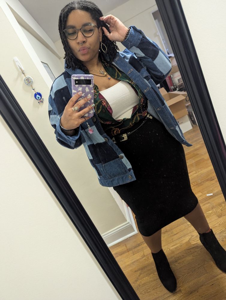 Me wearing a patchwork denim jacket, a 80s vintage red, blue, & green striped shirt w gold chains printed on it and a midi length  tight black skirt w black booties.