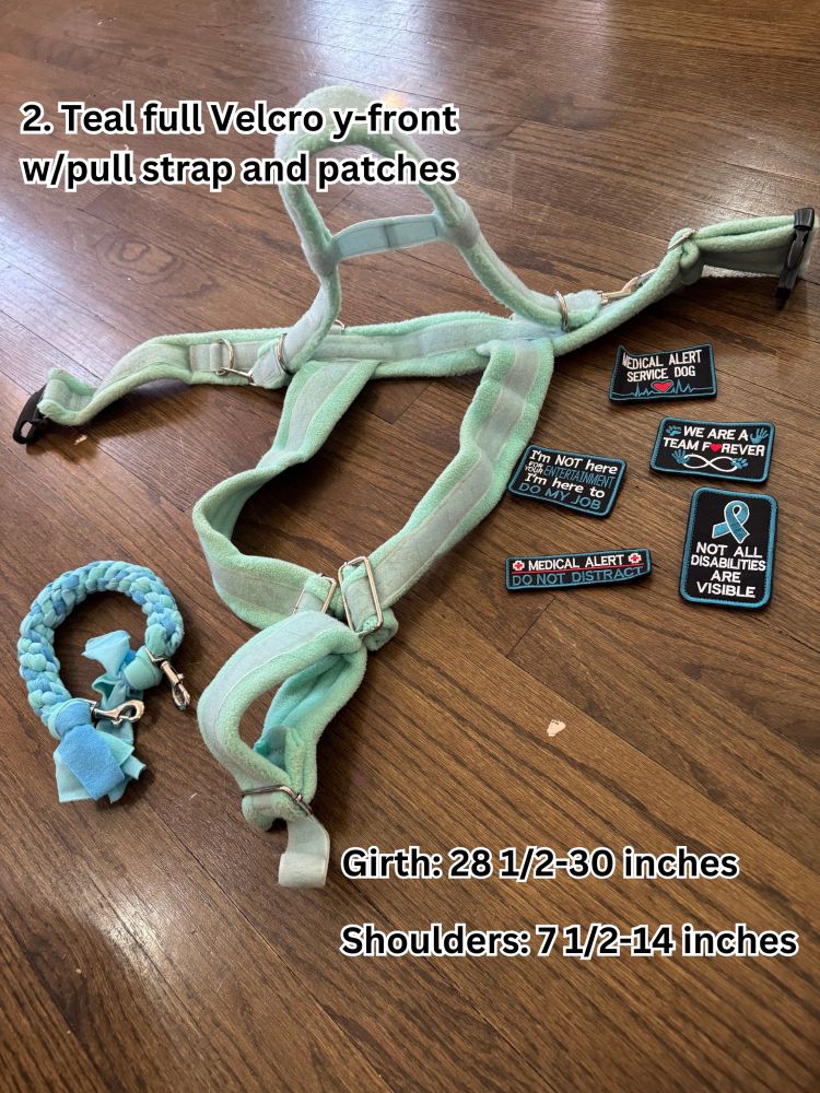A teal fleece harness completely covered in Velcro with a flexible counterbalance handle. A set of blue medical alert patches and a blue and mint fleece pull strap is to the side. The measurements are written as girth: 28.5-30 inches with shoulders at 7.5-14 inches.