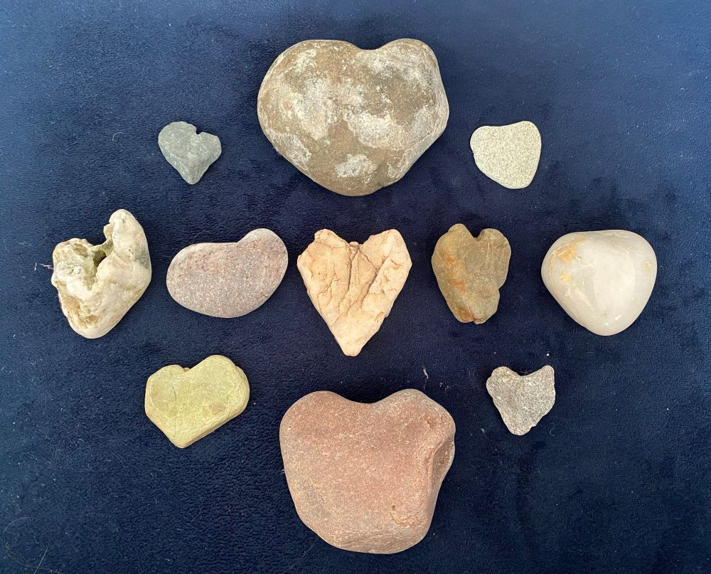 11 stones shaped like hearts arranged on a navy coloured background.