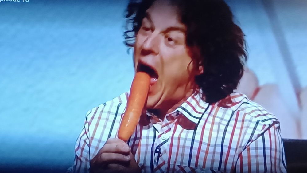 Alan Davies frå QI i ferd med å bita over ei gulrot på pinne