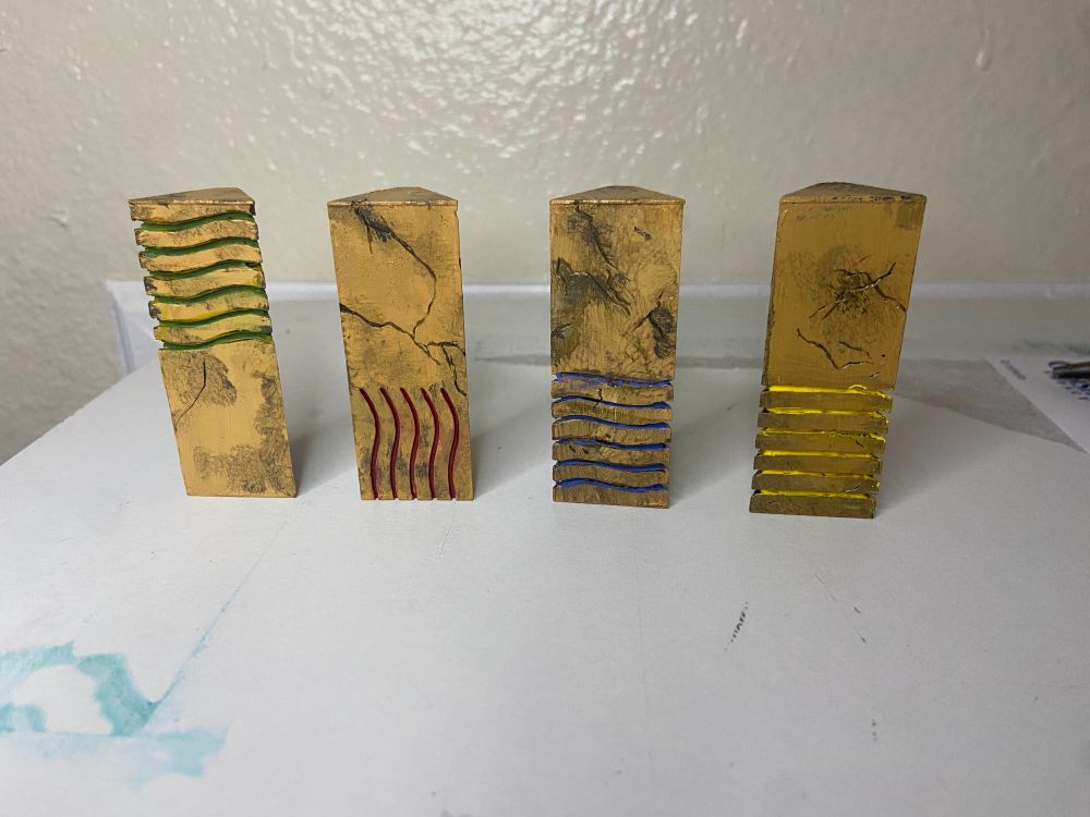 Set of the four elemental stones from The Fifth Element, painted in sandstone color, with the grooves painted roughly with primary colors. Wind, Fire, Water, and Earth 